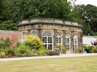 Orangery in the grounds of  Ripley Castle with a grass lawn in the foreground and trees in the background. 