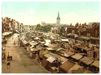 Old tinted postcard showing a busy market square full of stalls with awnings.