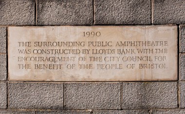 A carved stone reads '1990. The surrounding public amphitheatre was constructed by Lloyds Bank with the encouragement of the city council for the benefit of the people of Bristol.'