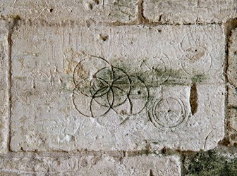 Daisy wheels scribed with a pair of compasses or dividers on a stone barn wall.