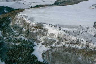 A promontory fort and hillside figure in snow.