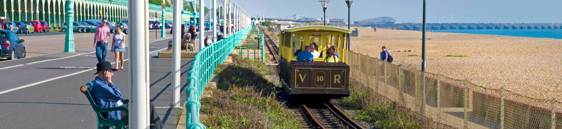 A small tourist train passing along Brighton seafront.