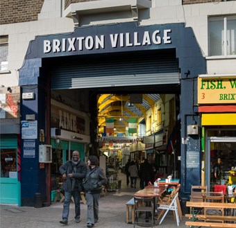 Indoor market stalls and shop fronts with a sign "Brixton Village"