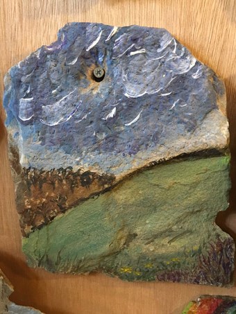 A stone roof tile reused by a 21st century artist to depict the rolling landscape of the Yorkshire Worlds with an expanse of sky above.