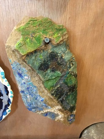A fragment of stone roof tile painted with a impressionistic landscape by a 21st-century artist.