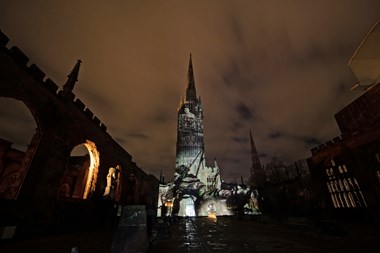 Image of a statue being hoist off the ground projected onto cathedral building