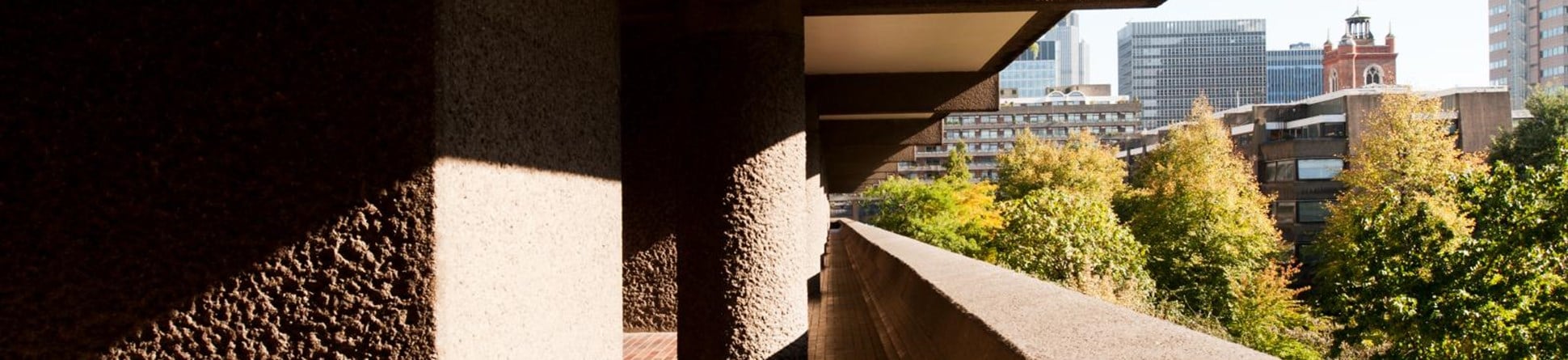 Terracotta tiled walkway along a line of bush-hammered concrete pillars.
