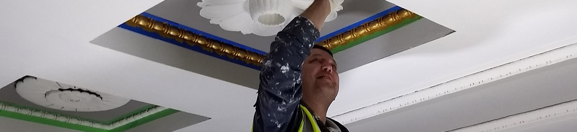 Photo of a painter touching up the ceiling using yellow paint