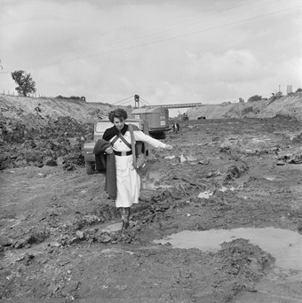 A female site nurse walks through mud on motorway construction site.