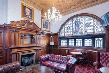 Ornate hardwood fire surround and furniture in a snug within a Victorian pub.