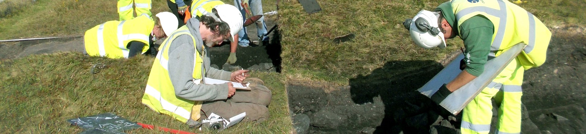 Archaeologists excavating and recording a barrow.
