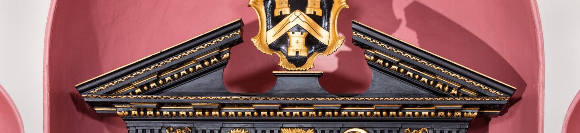 Coat of arms on top of a throne with masonic symbols underneath. Wood is black with gold leaf decoration.