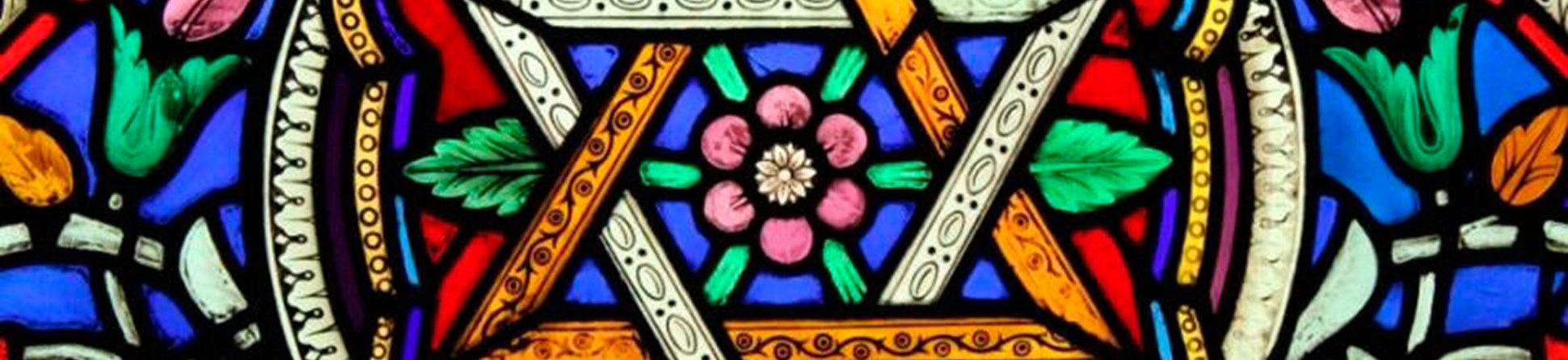 Stained glass window of a star shaped pattern with a flower in the centre and around the edges.