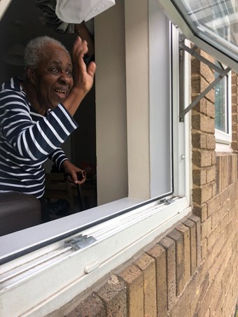 A 92 year old Ghanaian woman waving out her window.