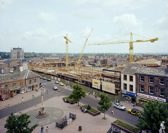 Colour photograph taken from a high vantage point, looking across the Market Place towards the construction of The Lanes Shopping Centre. Yellow cranes rise above the site.