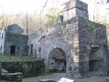The round headed arches formed in long rubble stones are a major visual feature, as seen in this view of the iron furnace from the lower east end of the site.