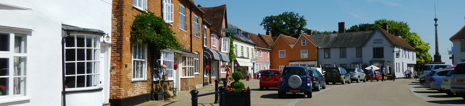 Road with houses and shops with parked cars outside