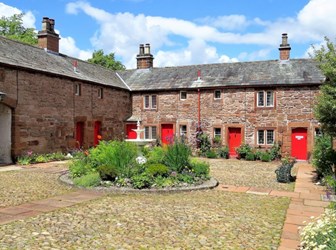 Almshouses built by Lady Anne Clifford for poor widows in Appleby. Stone cottages with red front doors around a courtyard with a fountain in the middle.