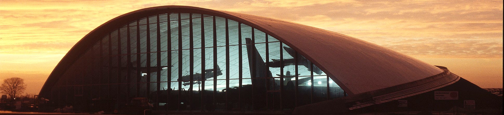 View of hangar at sunset with silhouettes of aircraft inside the building