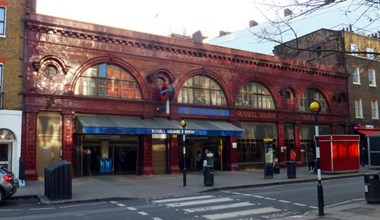 Red-tiled exterior of underground station viewed across a road with pelican crossing in foreground.