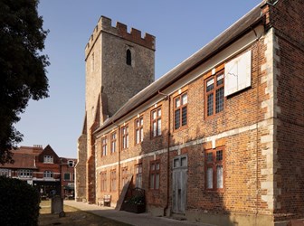 Side view of the Plume Library building, showing the church tower and red brick library building.