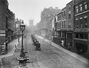 Old black and white photo of a cobbled street in Chester.