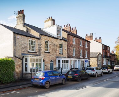 A row of historic vernacular buildings in different styles on a village High Street.