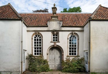 Archway door to the entrance with arched windows on either side and a window above the door