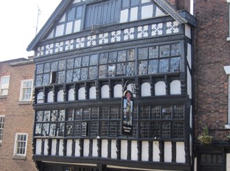 A man standing outside looking through a window of the Bear and Billet pub in Chester