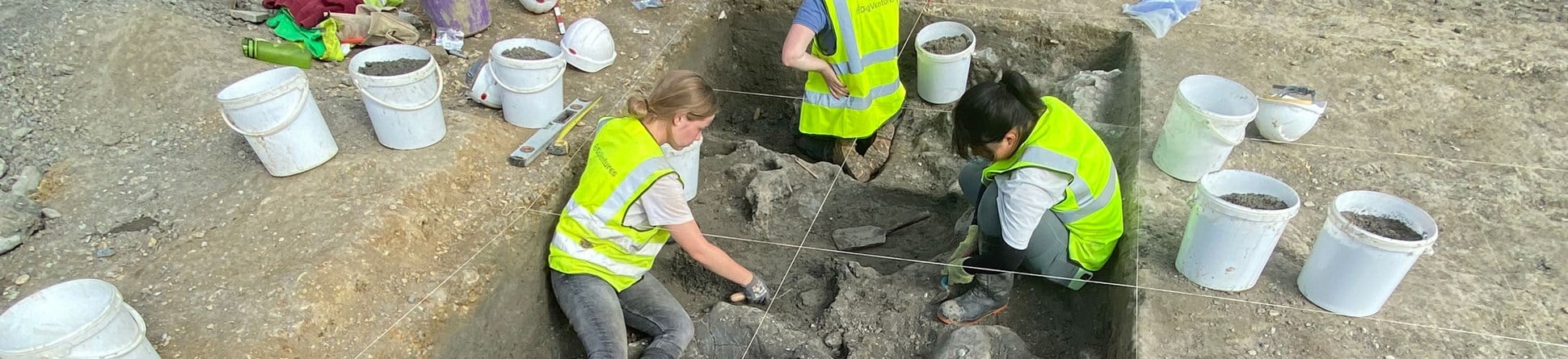 Four archaeologists excavating a trench.