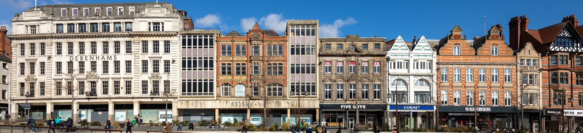 A series of historic shop fronts in a pedestrianised area of a city.