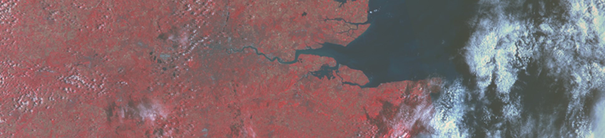 High level satellite image showing the south-east of England in various shades of red with banks of white cloud to right