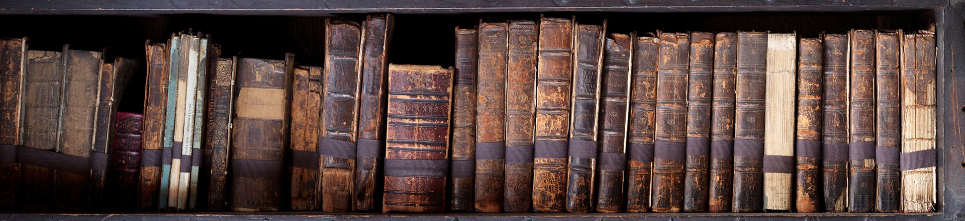 Old leather-bound books on three shelves of Chetham's Library, Long Millgate, Manchester.