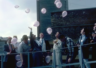 A group of men and women celebrating outside a building.