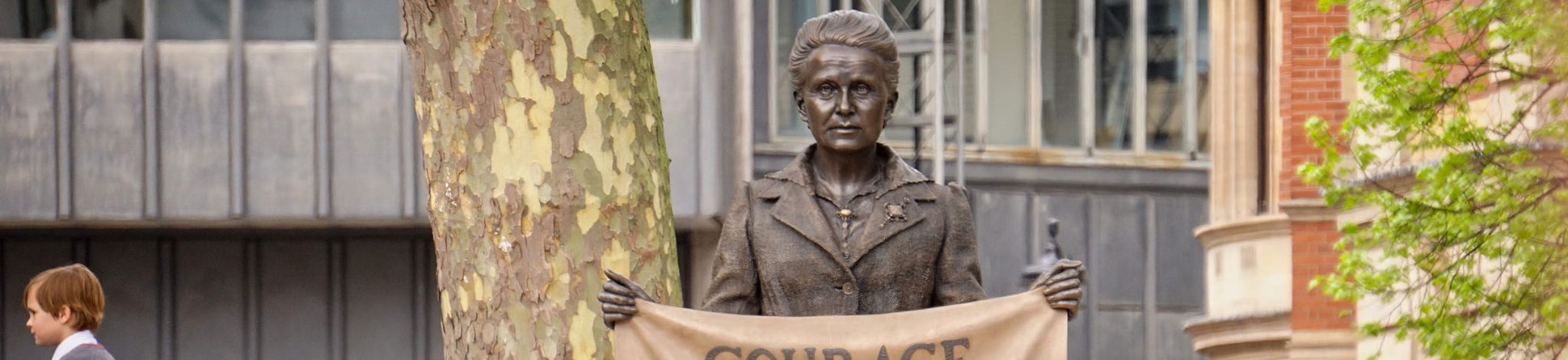 Statue of Millicent Fawcett holding a banner that displays text:
"Courage calls to courage everywhere"