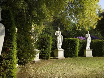 A semi-circle of yew hedging with niches containing statuary and sphinxes.