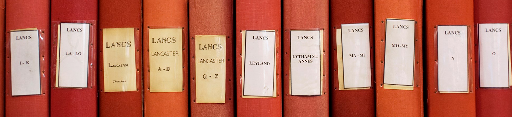 Red boxes on a shelf labelled with Lancashire placenames, part of the Architectural Red Box Collection.