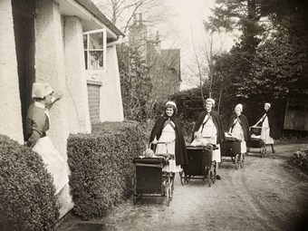Sister Arnold watching the return of some of her nurses from taking the children out in the prams