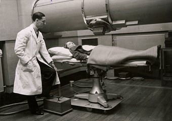 A patient lying beneath the x-ray tube while an operator adjusts the position of the tube