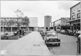 archive black and white photograph of a street scene with people and vehicles
