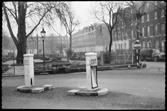 archive black and white photograph of street furniture including traffic bollards, no-entry sign and a streetlamp.