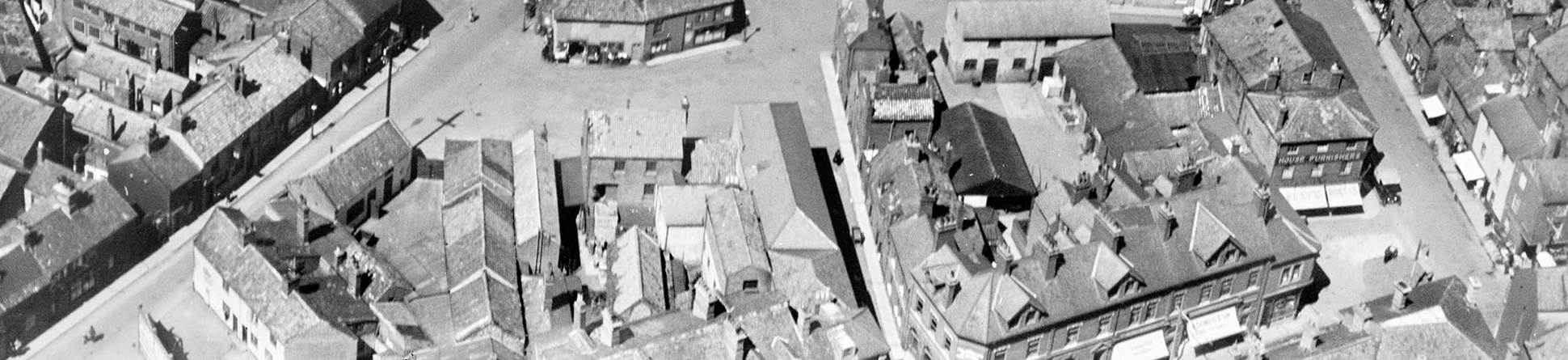 Photo shows a black and white aerial photo of residential, religious and industrial buiildings