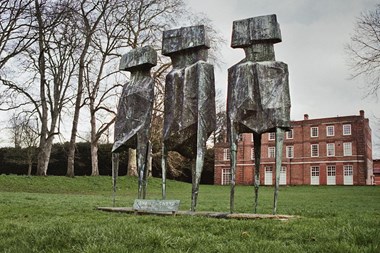 Sculpture of three figures standing in field