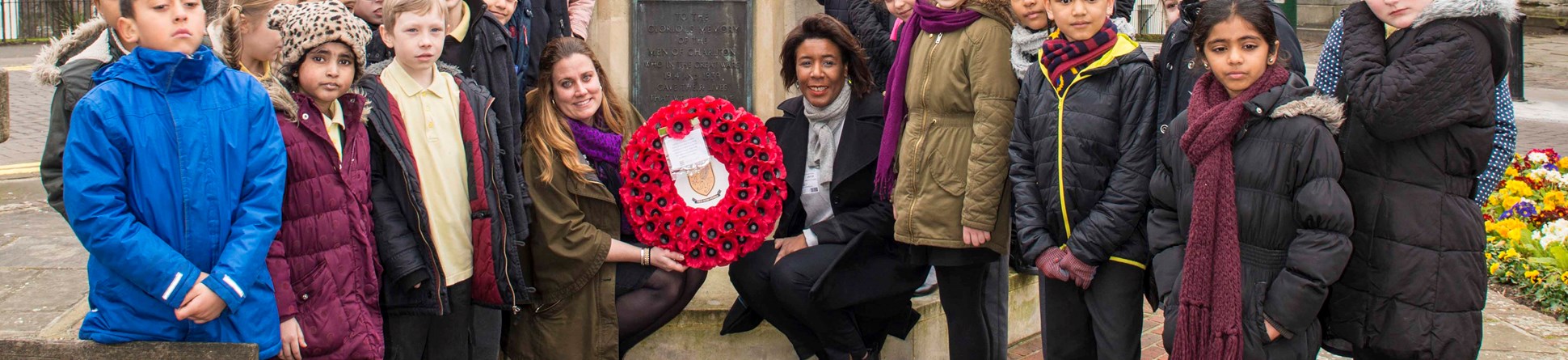 Children from Charlton Manor Primary School, Tiva Montalbano First World War Programme Manager at Historic England and Cllr Denise Scott-Mcdonald gather at the war memorial to lay a wreath.