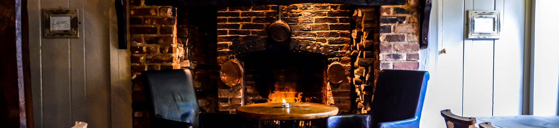 Armchairs in front of an open fire in the Hat Rack bar