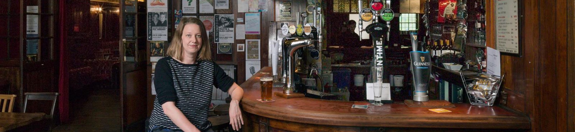 Tessa Blunden sitting at the bar of the Ivy House Community Pub of which she is co-founder. 