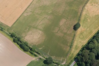 Colour aerial photo showing arable fields with the archaeology seen as darker lines against a generally paler background