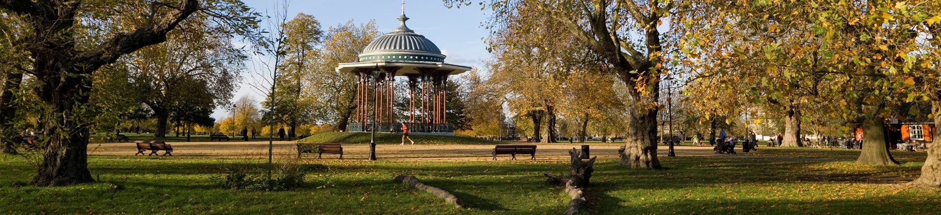 A jogger running past a bandstand at Clapham Common