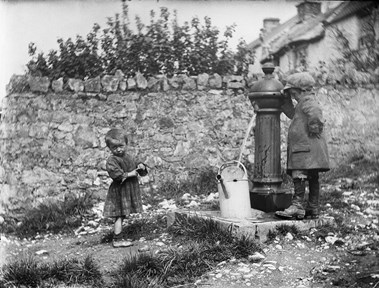 Two children collecting water at pump