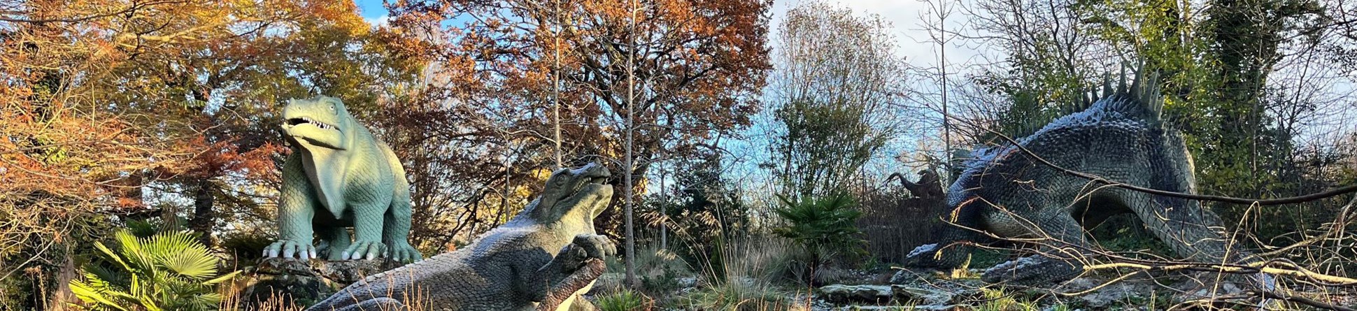Photograph of three large Dinosaur sculptures in a wintry landscape.